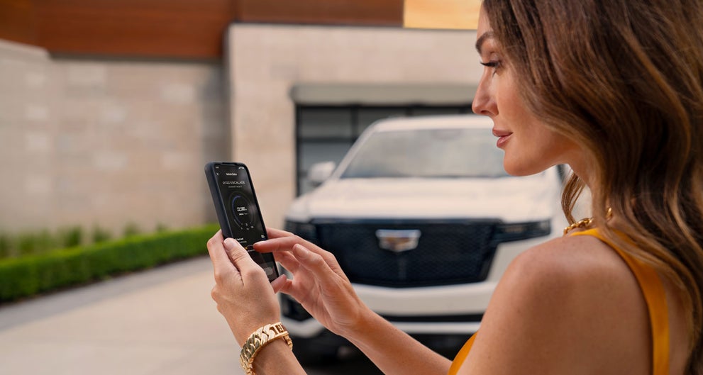 lady checking her mobile with a Cadillac vehicle background | Serra Cadillac in Washington MI